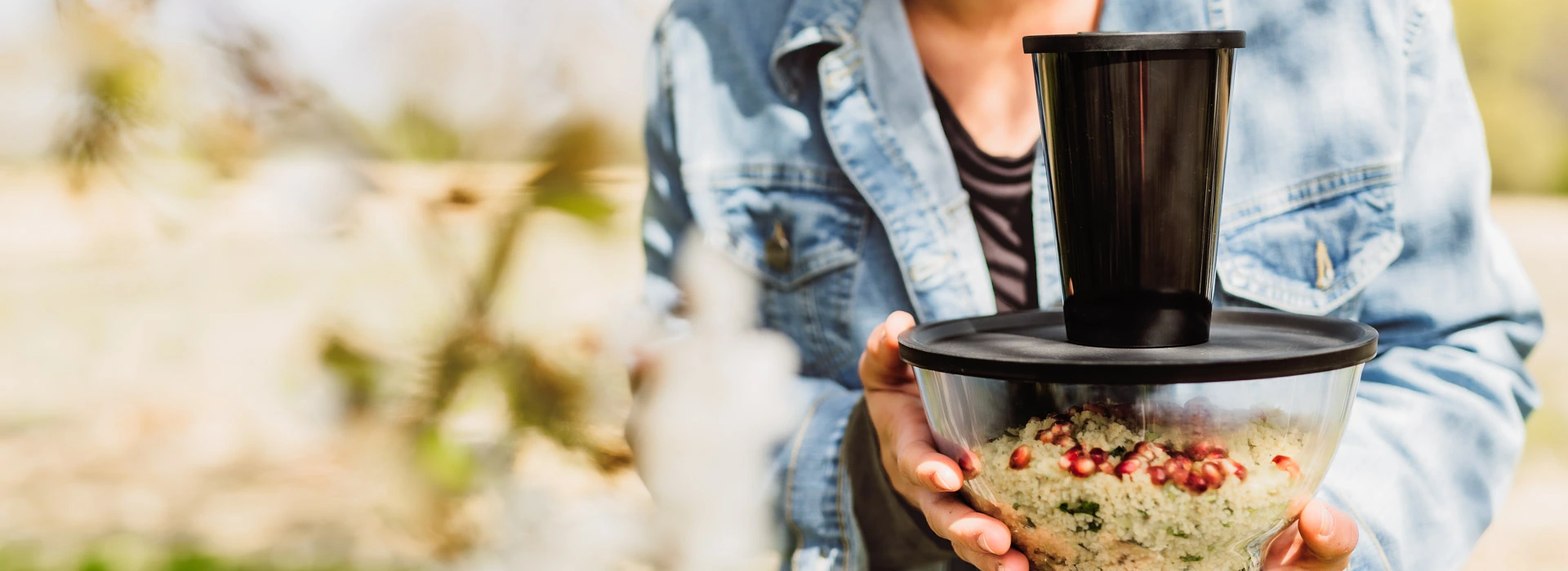 ORNAMIN-to go-Mehrweggeschirr im Set für das Essen und Trinken zum Mitnehmen Eine verschlossene Mehrwegschale und ein Coffee to go-Becher in den Händen einer Person