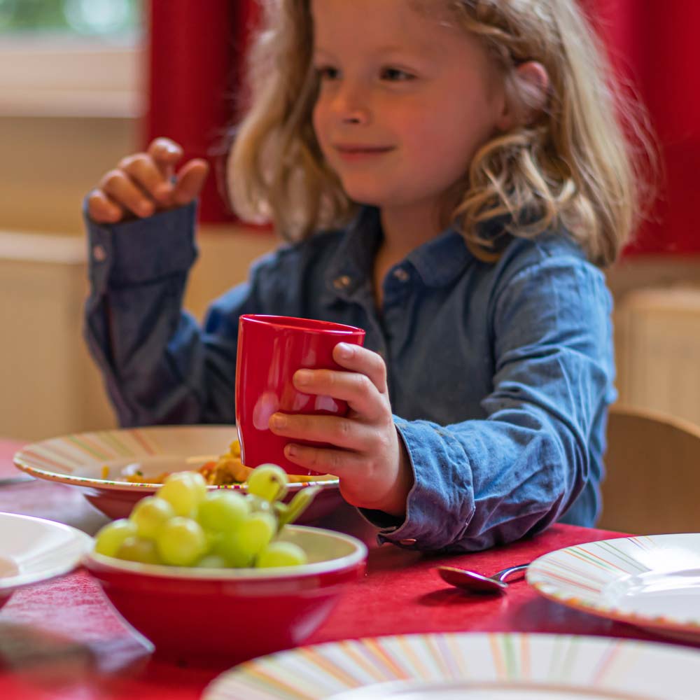 ORNAMIN-Mehrweg-Kindergeschirr-Referenz-Kita-Marienkäfer Ein Kind in der Kita trinkt aus einem ORNAMIN Mehrweg Kinderbeher