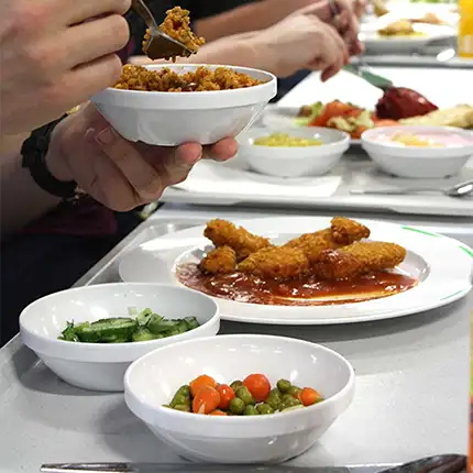 ORNAMIN-Mensa-Referenz des Studierendenwerkes Bielefeld Teller und Schalen mit Mittagessen stehen auf einem Tablett h in der Mensa