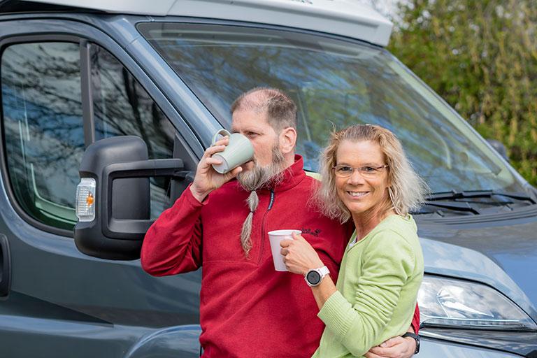 ORNAMIN Coffee to go Becher Paar steht mit ORNAMIN Coffee to go Bechern vor Camper