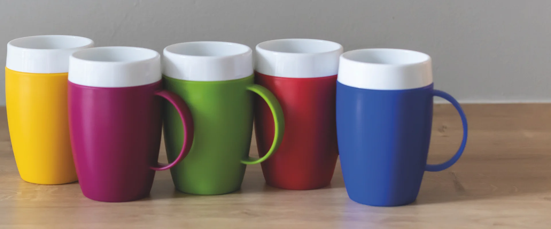 Bunte Becher auf dem Tisch. Colourful mugs on a table.