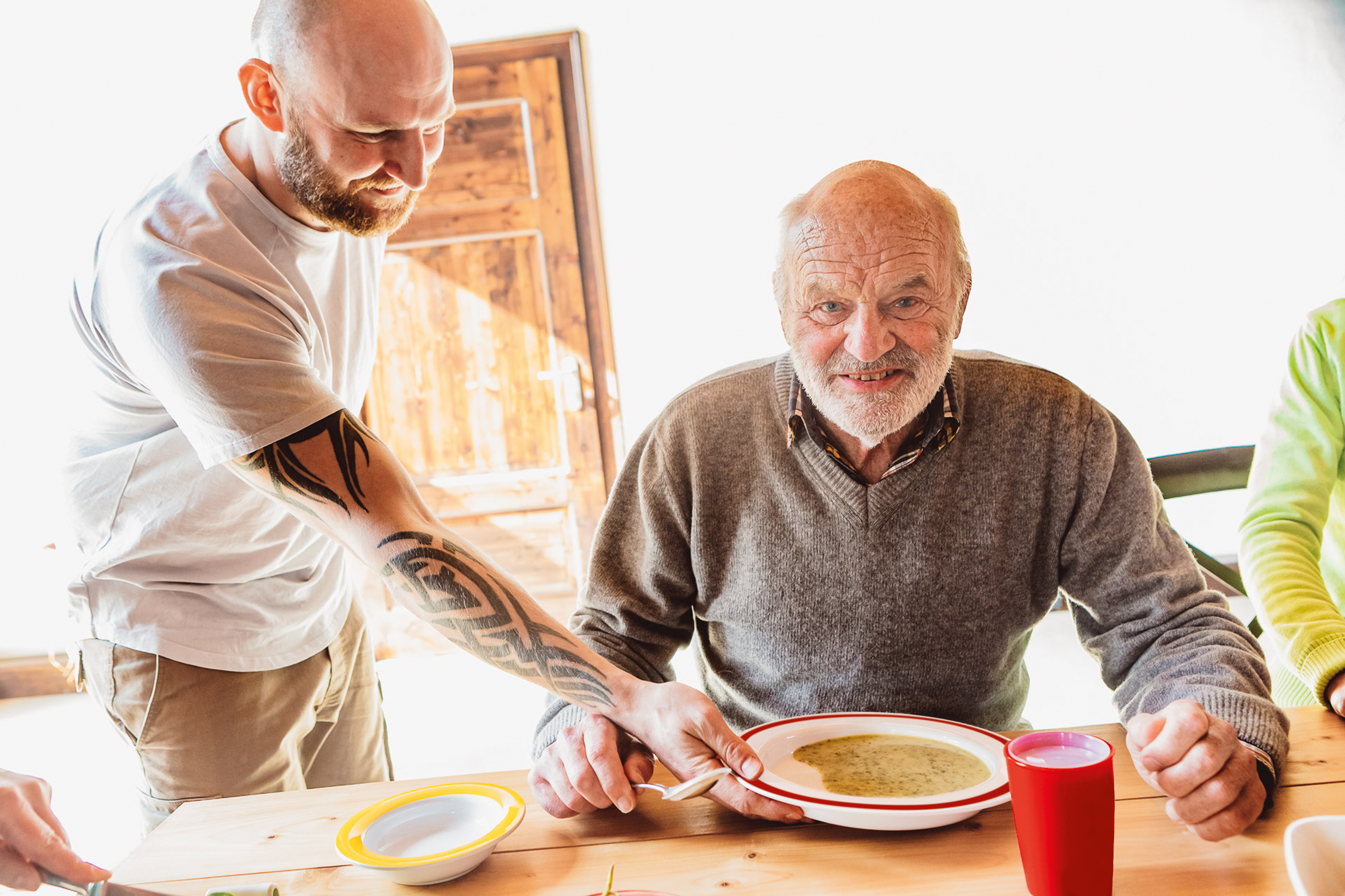 Ein Pflege serviert einem Pflegebedürftigen eine Suppe