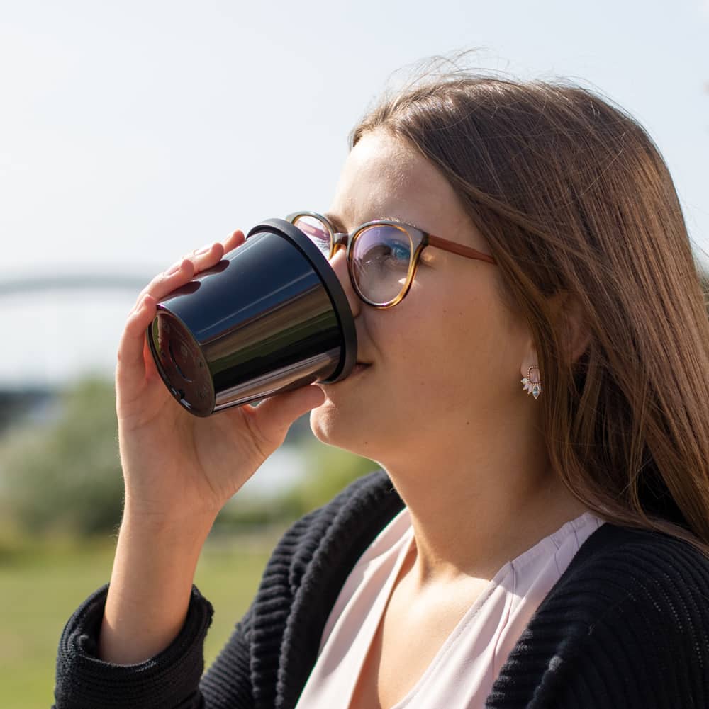 ORNAMIN Coffee To go Becher aus dem eine junge Frau trinkt