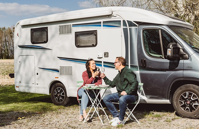 ORNAMIN-Camping-Outdoorgeschirr für den Camper Ein Pärchen sitzt vor einem Wohnmobil und stößt mit bruchstabilen Sektgläsern an.