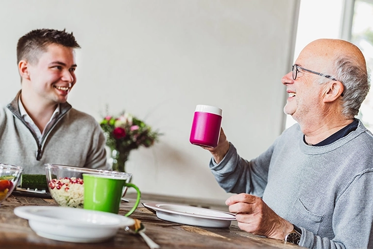 Ein junger und ein alter Mann zusammen am Esstisch. A young and an old man together at the dining table.