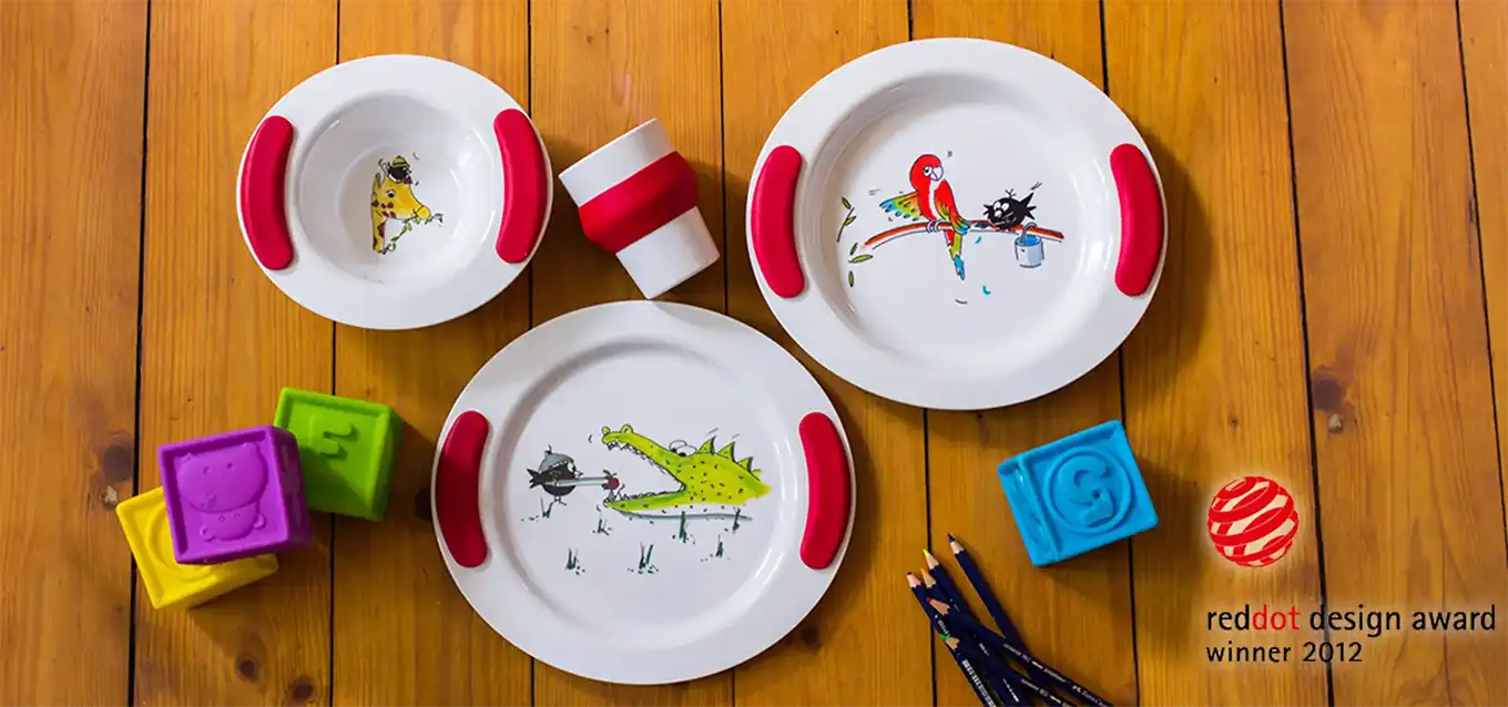 Kindergeschirr-Set bestehend aus Becher, Tellern und Schale mit Tiermotiven und roten Griffkissen