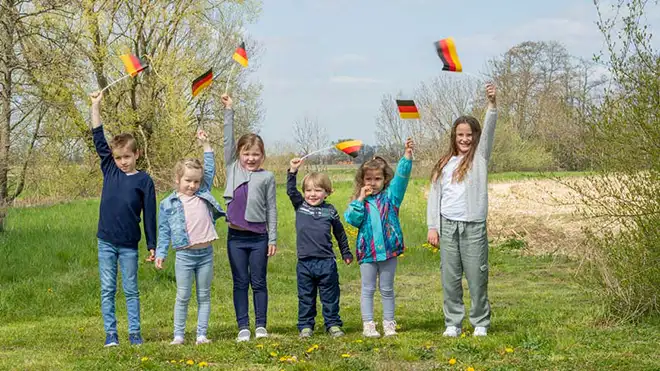 ORNAMIN-Mehrweggeschirr-Made-in-Germany Kinder auf einer Wiese mit Deutschlandflaggen