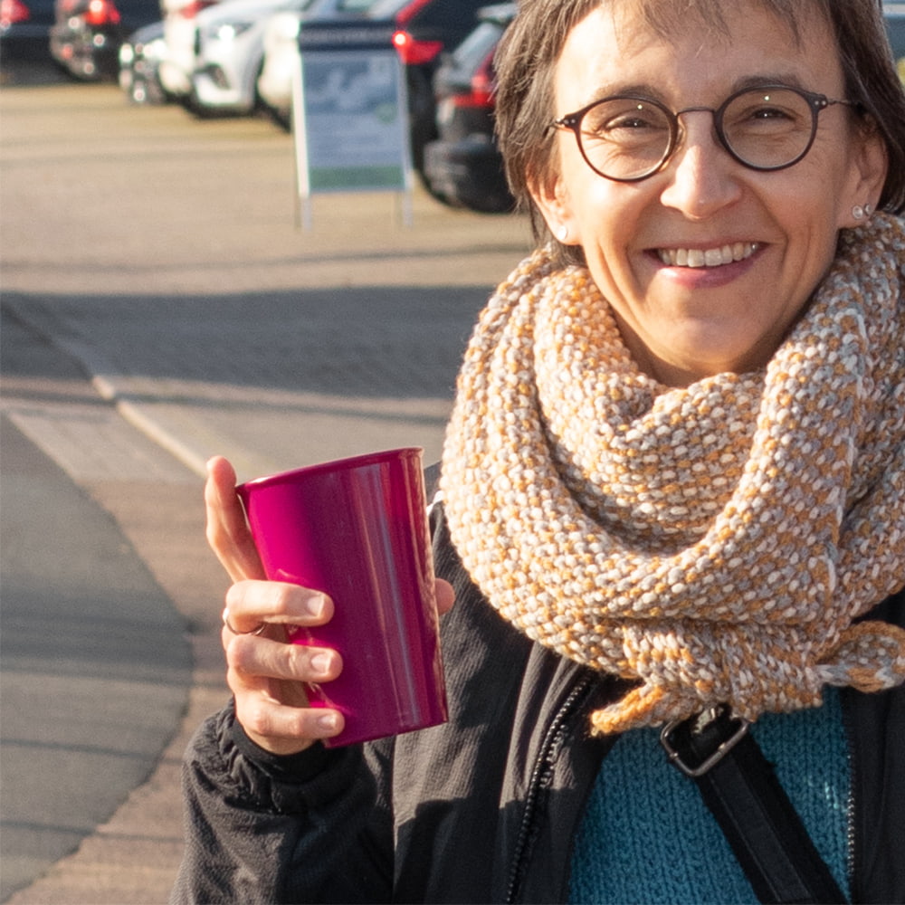 ORNAMIN-m1210-154-coffee-to-go-online-01 ORNAMIN Coffee To go Mehrwegbecher in brombeer mit einer lachenden Frau