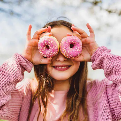 Kind hält sich zwei Donuts vor die Augen