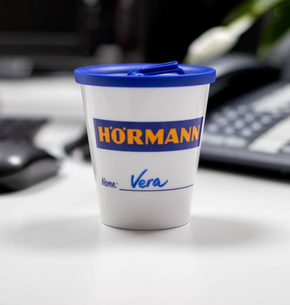 ORNAMIN-Mehrwegsystem-für-Unternehmen-Coffee-to-go-Referenz-Hoermann ORNAMIN-Coffee-to-go-Mehrwegbecher-im-Design-von-Hoermann-bechriftet-mit-dem-Namen-einer-Mitarbeiterin
