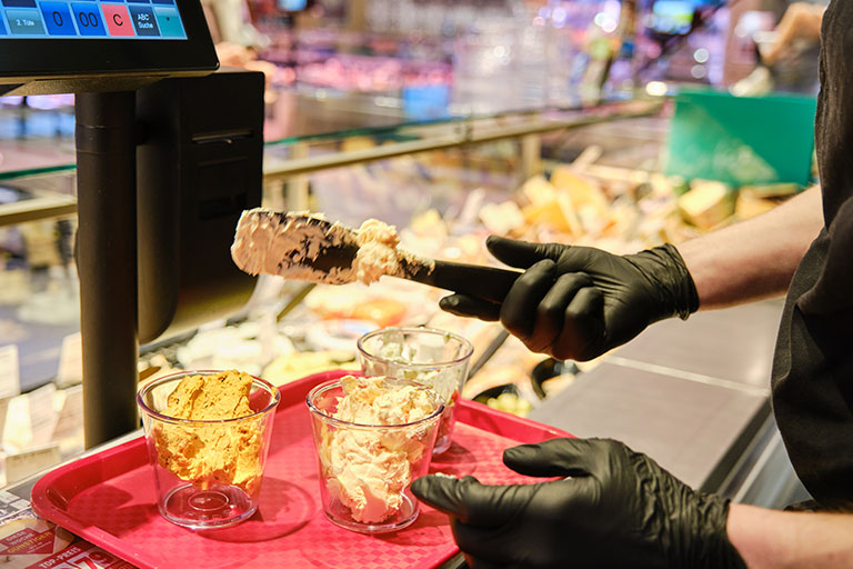 Mann wiegt Dips in ORNAMIN Schalen an Frischetheke ab