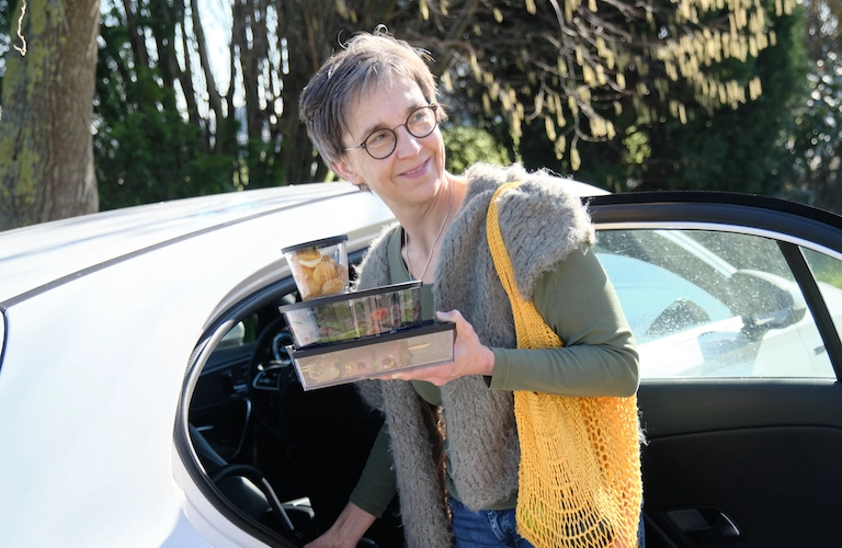 Frau am Auto mit gefüllten Boxen