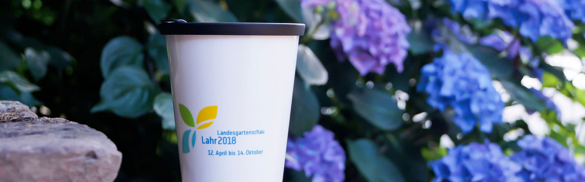 ORNAMIN-Referenzen-Landesgartenschau-Lahr ORNAMIN-To-go Mehrwegbecher Great Gloria mit Dekor vor Blumen
