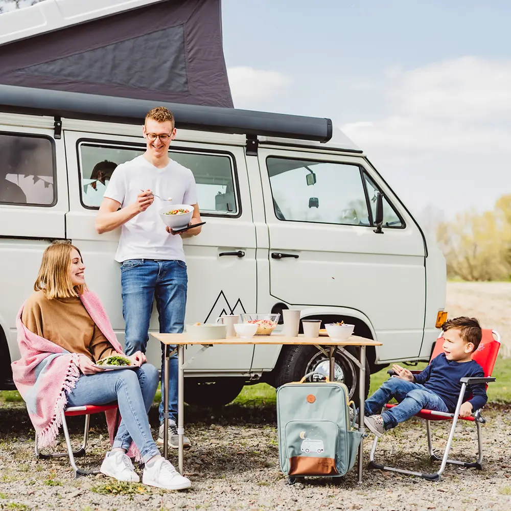 Eine Familie am gedeckten Tisch vor ihrem Wohnmobil