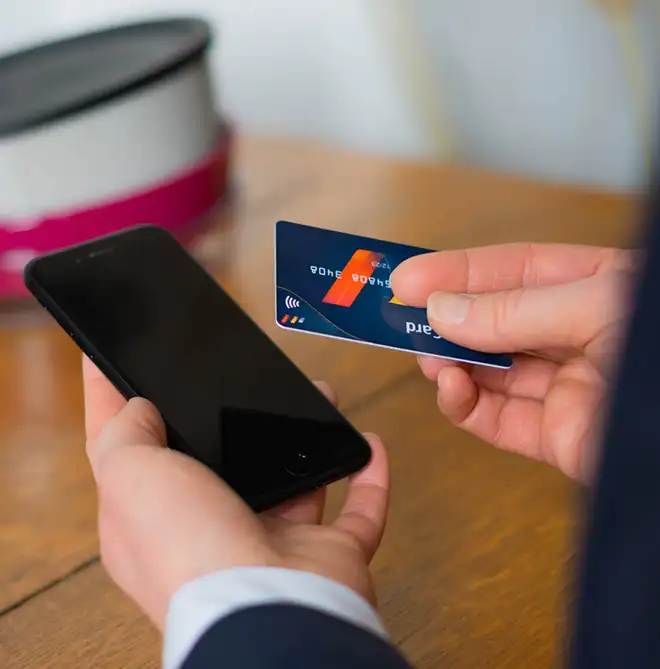 ORNAMIN-FAQ-zum-Thema-Zahlung Person mit Kreditkarte und Handy prüft Zahlungsmöglichkeiten