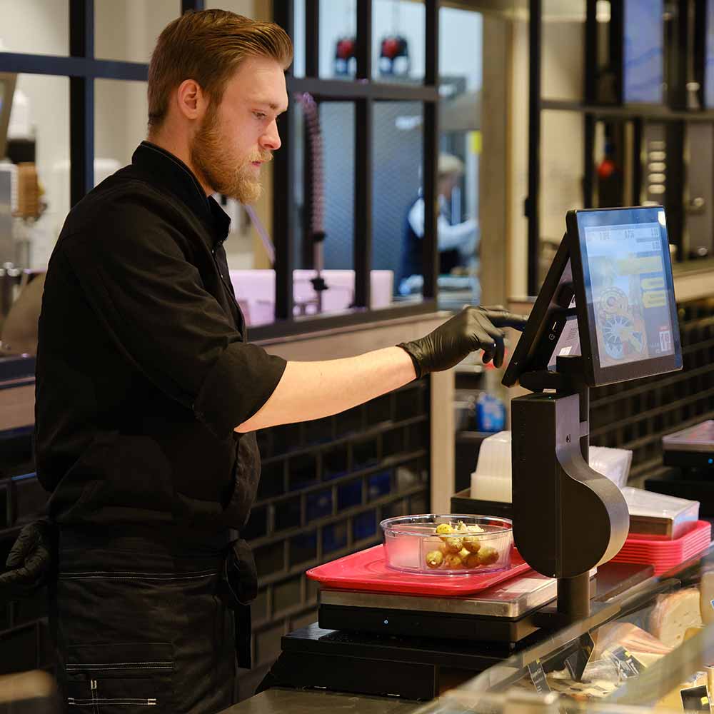 Mann wiegt Oliven in ORNAMIN To go Schale ab