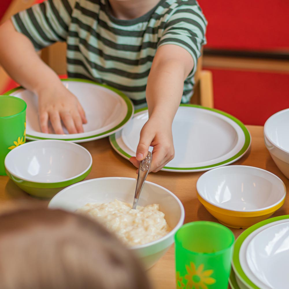 ORNAMIN-Mehrweg-Kindergeschirr-Referenz-Kita-Loewenzahn ORNAMIN Mehrweg Kinderteller Kinderschalen und Kinderbecher auf einem Esstisch in der Kita