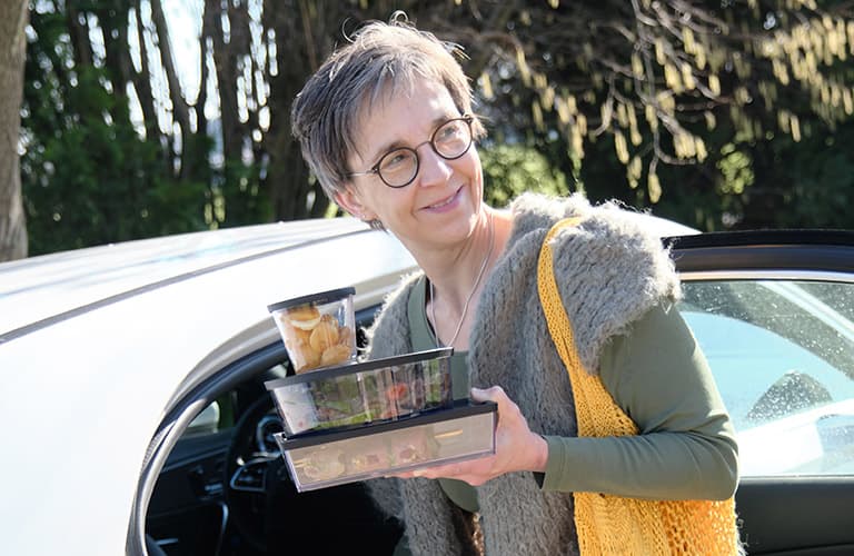 Frau steigt mit ORNAMIN Mehrwegschalen ins Auto