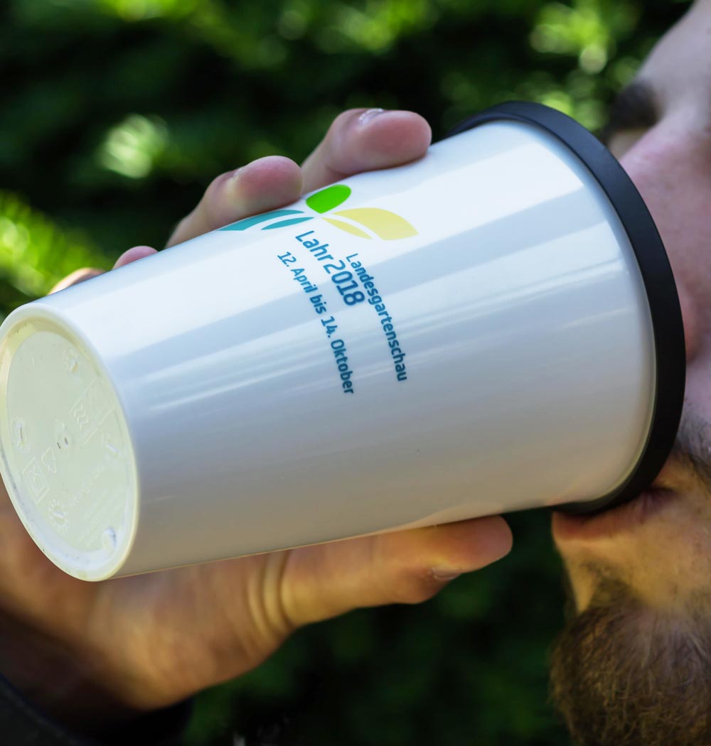 ORNAMIN-Coffee-to-go-Mehrwegbecher-Referenz-Landesgartenschau-Lahr Person trinkt aus einem ORNAMIN Coffee to-go Mehrwegbecher